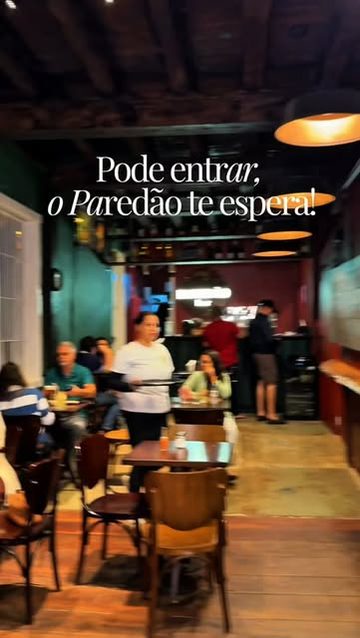 Salão do Paredão Bar com mesas de madeira e luminárias